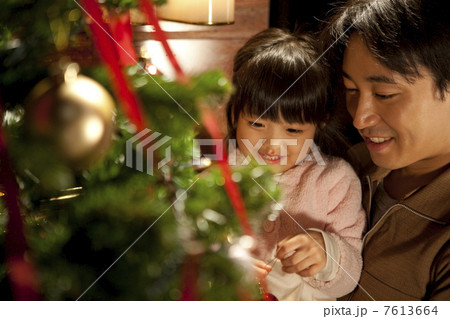 クリスマスツリーの飾りつけをする娘と父 7613664