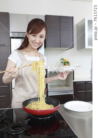 パスタを盛り付けようとする女性 7613725