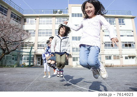 大縄跳びをする小学生と教師の写真素材