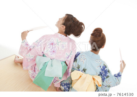 座って団扇で扇ぐ浴衣女性2人の後姿 7614530