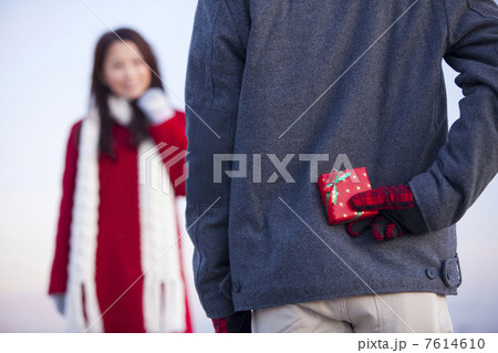 女性にプレゼントを渡そうとする男性の後ろ姿 7614610