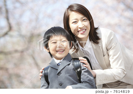 桜の下に立つ小学生男子と母親のポートレート 7614819