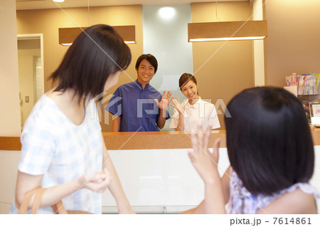 歯医者を出ようとする親子と手を振る歯科スタッフ 7614861