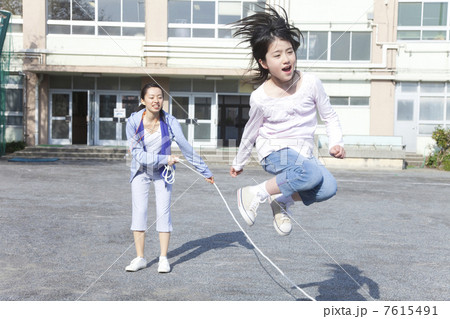大縄跳びをする小学生と教師 7615491