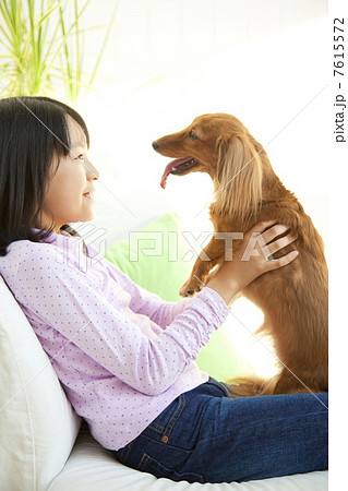 ミニチュアダックスフントを抱く笑顔の女の子 7615572