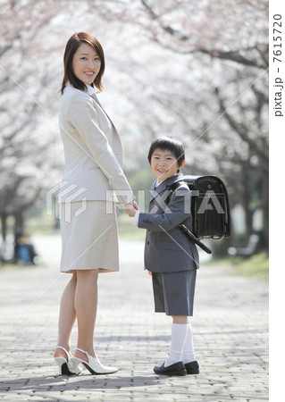 桜並木の下で振り返る小学生男子と母親 7615720