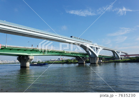 扇大橋を通行中の舎人ライナーと鋼材船 7635230