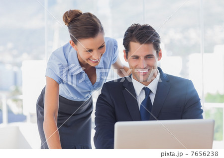 Happy business people looking at laptop and smiling Happy business people looking at laptop and smiling 7656238