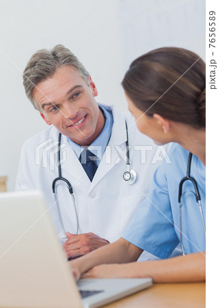 Two smiling doctors working on a laptop Two smiling doctors working on a laptop 7656589