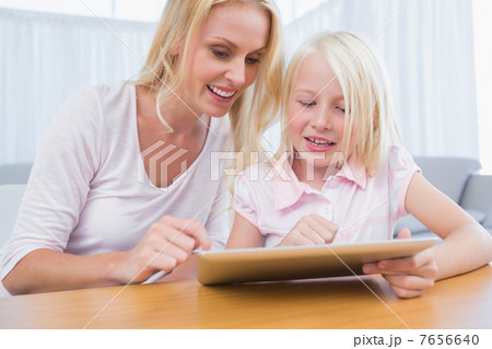 Cheerful mother and daughter using digital tablet 7656640