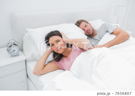Snoring man is annoying his wife who tries to sleep 7656807