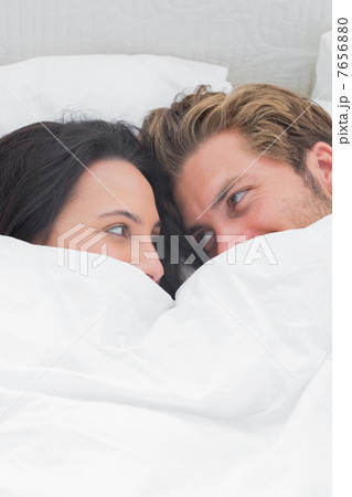 Couple under the quilt looking at each other 7656880