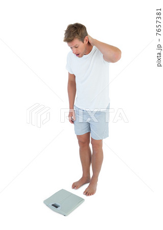 Man being astonished while looking at a weighing scale Man being astonished while looking at a weighing scale 7657381