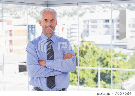 Businessman smiling at camera with arms crossed 7657634