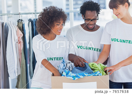Cheerful volunteers taking out clothes from a donation box 7657638