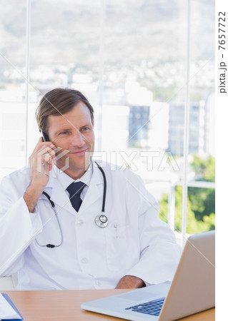 Cheerful doctor phoning in his office Cheerful doctor phoning in his office 7657722