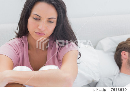 Thoughtful woman sat on her bed 7658650