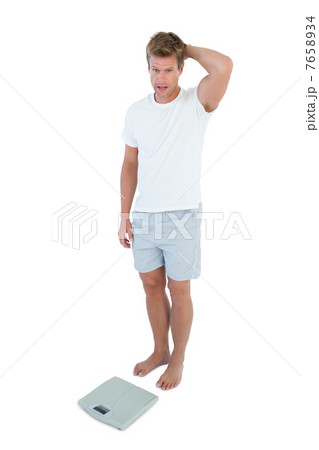 Man shocked in front of a weighing scale Man shocked in front of a weighing scale 7658934