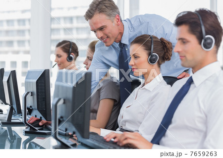 Smiling manager helping call centre agent Smiling manager helping call centre agent 7659263
