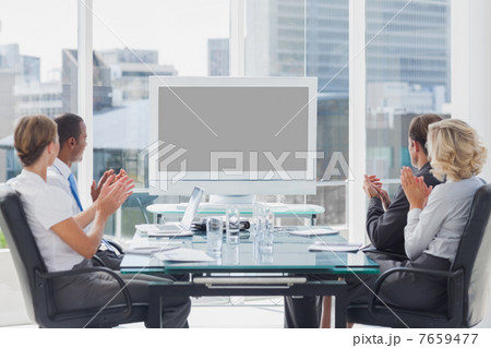 Business people applauding at a screen Business people applauding at a screen 7659477
