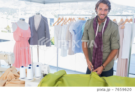 Handsome fashion designer cutting textile 7659620