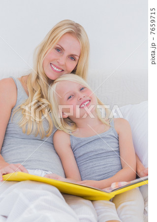 Mother holding a story book with her daughter Mother holding a story book with her daughter 7659715