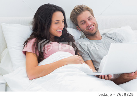 Couple in bed looking at their laptop Couple in bed looking at their laptop 7659829