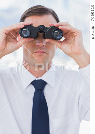 Serious businessman using binoculars 7660119
