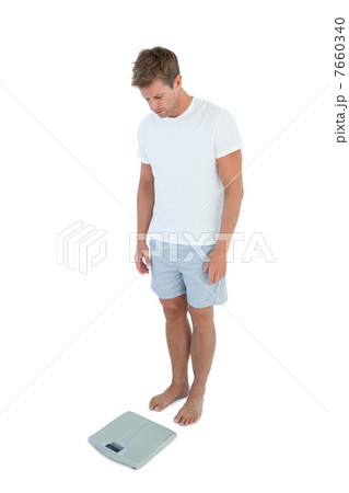 Athletic man looking at a weighing scale 7660340