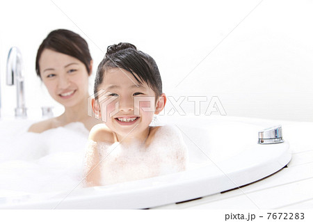 泡風呂に入る女の子と母親の写真素材