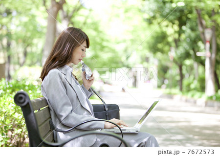 ベンチでノートパソコンを操作するビジネスウーマン 7672573