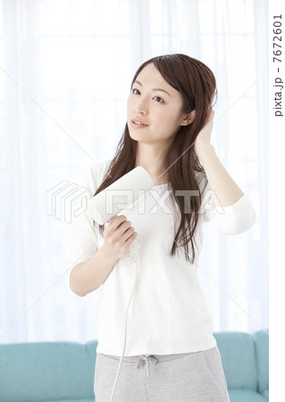 ドライヤーで髪を乾かす女性 7672601