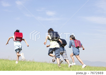走っている小学生4人の後姿の写真素材