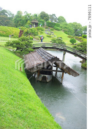 五月雨の後楽園に繋がれる小舟(縦位置） 7696111