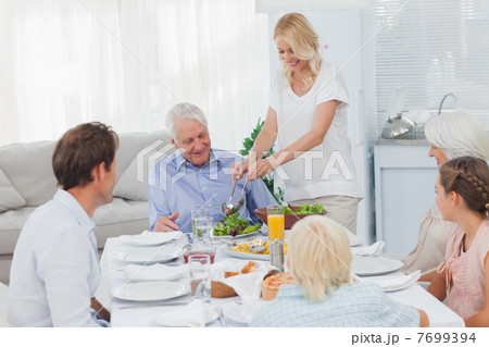 Woman serving salad at the dinner table 7699394
