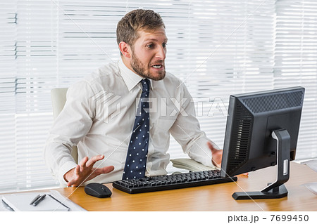 Frustrated businessman looking at his computer 7699450