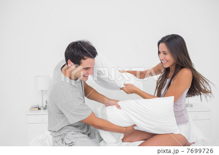 Couple having fun with a pillow fight 7699726