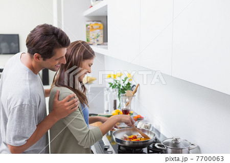 Man looking at his wife cooking 7700063