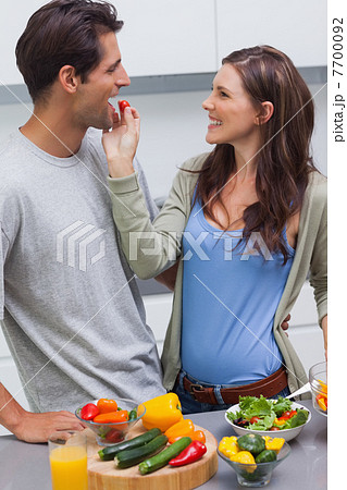 Attractive woman feeding her husband cherry tomato Attractive woman feeding her husband cherry tomato 7700092