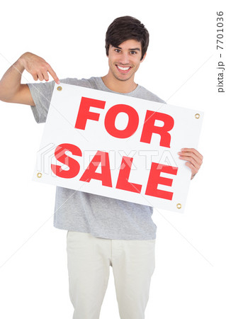 Smiling man pointing at for sale sign 7701036