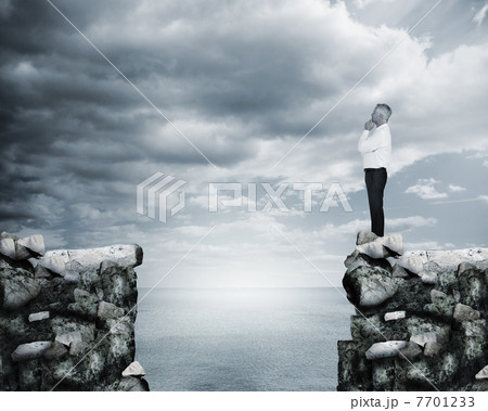 Businessman thinking at the edge of a cliff Businessman thinking at the edge of a cliff 7701233
