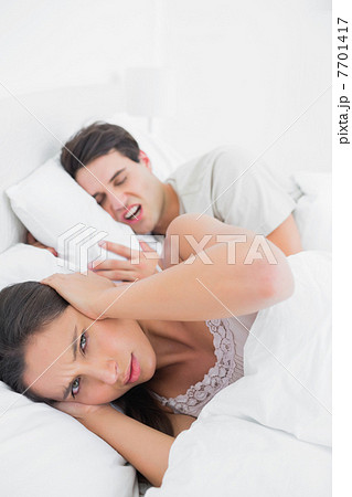 Pretty woman covering ears while her partner is snoring 7701417