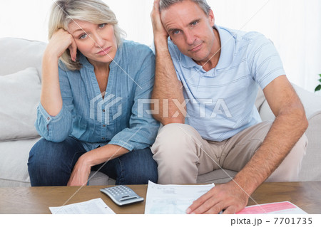 Anxious couple going over bills looking at camera 7701735