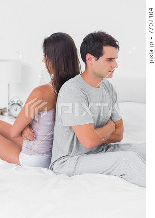 Angry couple ignoring each other sitting back to back on bed Angry couple ignoring each other sitting back to back on bed 7702104