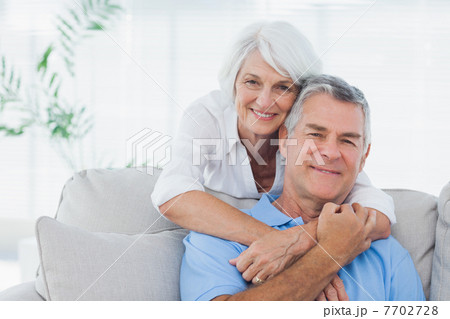 Woman embracing husband sitting on the couch Woman embracing husband sitting on the couch 7702728