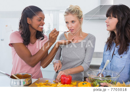 Cheerful friends preparing a meal together Cheerful friends preparing a meal together 7703018