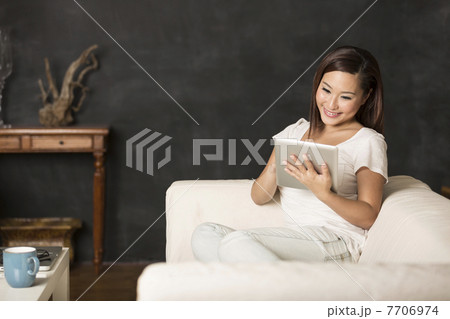 Chinese woman sitting on sofa using Digital Tablet Chinese woman sitting on sofa using Digital Tablet 7706974