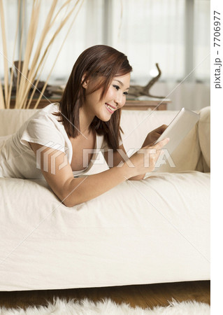 Chinese woman sitting on sofa using Digital Tablet 7706977