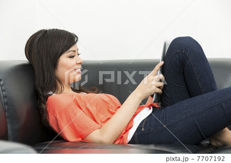 Young Chinese woman at home using a Digital Tablet Young Chinese woman at home using a Digital Tablet 7707192