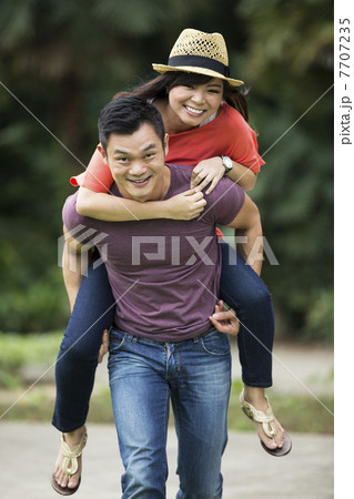 Portrait of a Chinese man giving a piggyback to his girlfriend 7707235